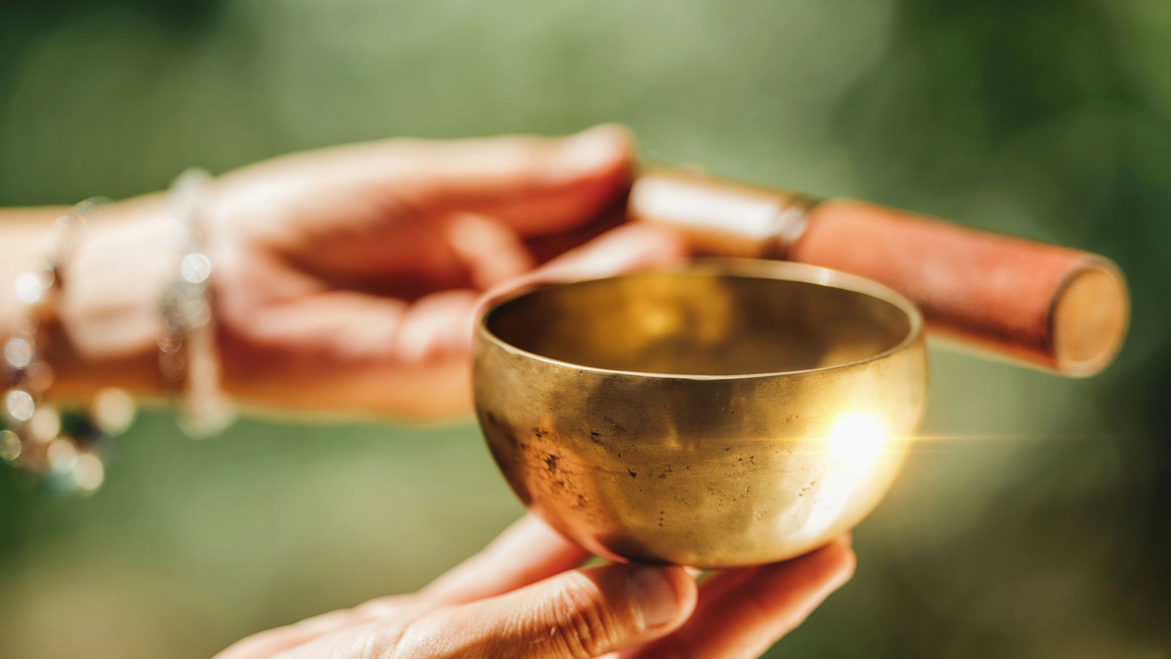 Hands playing a Tibetan singing bowl in nature